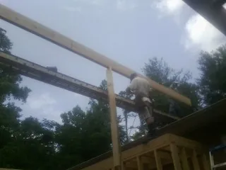 Carpenter setting a ridge beam over a new addition frame — Ice Dam Removal by Roofing Brothers in Lytle Creek