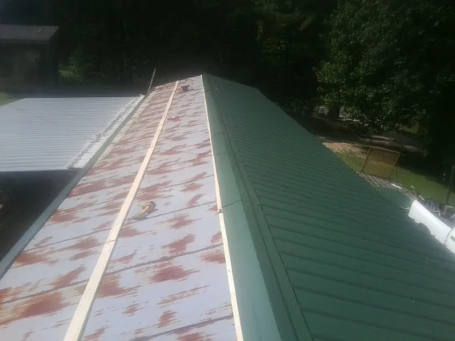 Old rusted panels beside newly installed green metal roofing — Wind Damage Roof Repair by Roofing Brothers in Lytle Creek