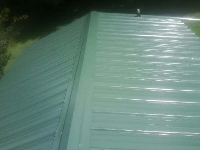 New green metal panels meeting at the ridge of a roof — Flat Roof Repair work by our crew in Lytle Creek