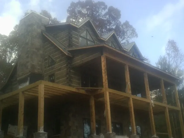 Stone chimney and dormers on a large log home with a timber porch in Lytle Creek