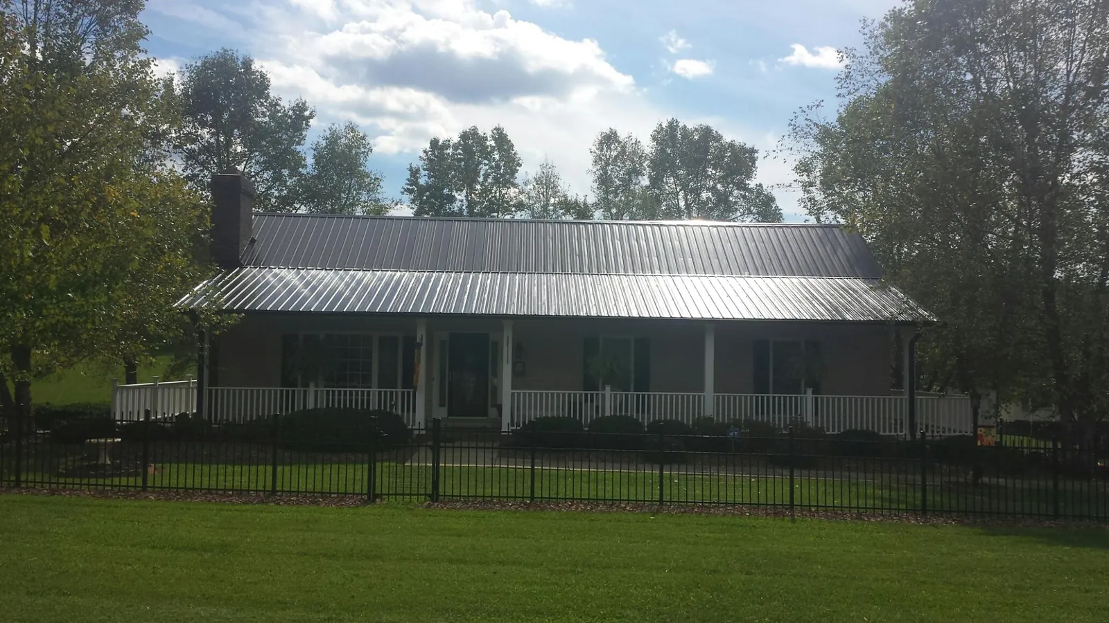 Gray metal roof on a brick ranch with a full width front porch — Gutter Guard Installation work by our crew in Lytle Creek