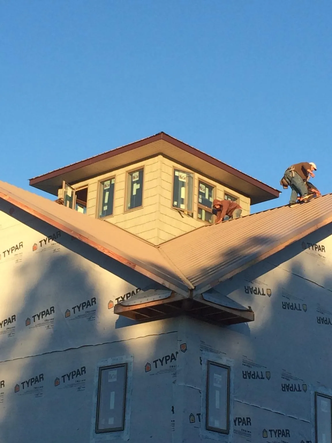 Roofers working around a rooftop cupola on a new metal roof at sunset — Roof Waterproofing in Lytle Creek by Roofing Brothers